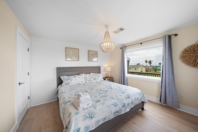 bedroom with light hardwood / wood-style flooring and a chandelier