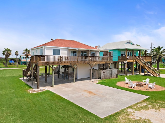 back of house featuring a wooden deck, a lawn, a patio, and an outdoor fire pit