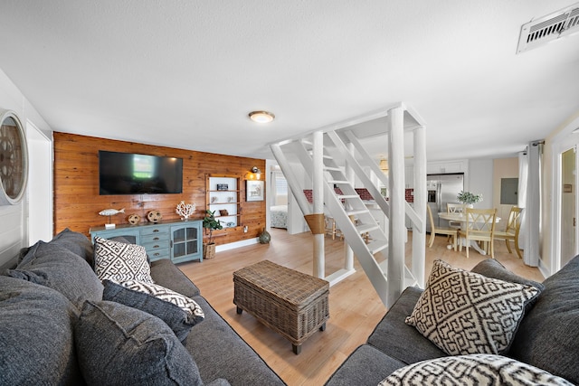 living room featuring a textured ceiling, hardwood / wood-style floors, and wooden walls