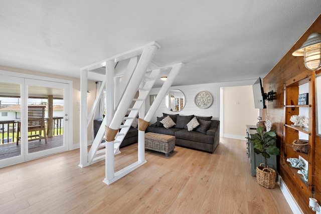 417 Olive St, Surfside Beach, TX 77541 - living area with baseboards, wooden walls, light wood-type flooring, and stairway