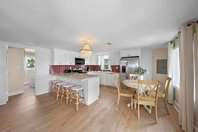 kitchen featuring light wood-type flooring, appliances with stainless steel finishes, white cabinetry, and a wealth of natural light