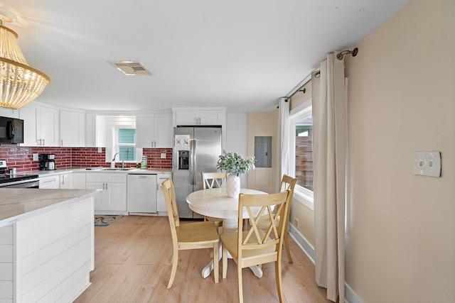 dining area with light wood-type flooring, an inviting chandelier, and sink