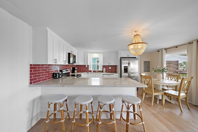 417 Olive St, Surfside Beach, TX 77541 - kitchen with stainless steel appliances, a peninsula, plenty of natural light, and white cabinets