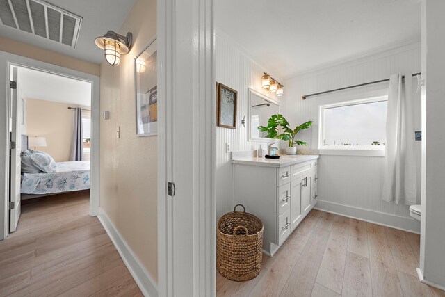 417 Olive St, Surfside Beach, TX 77541 - bathroom with hardwood / wood-style flooring, vanity, visible vents, connected bathroom, and baseboards