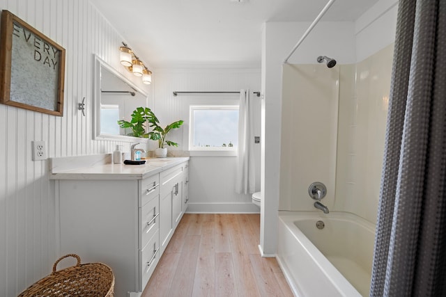 full bathroom with vanity, hardwood / wood-style floors, toilet, ornamental molding, and washtub / shower combination