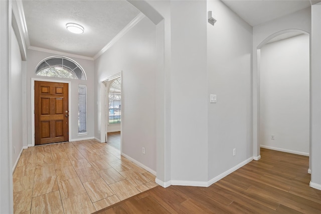 foyer entrance with crown molding, a textured ceiling, and light wood-type flooring