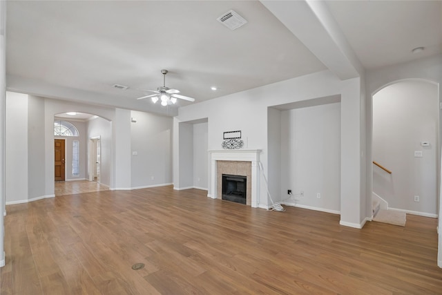 unfurnished living room featuring ceiling fan, a fireplace, and light wood-type flooring