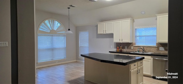 kitchen with white cabinetry, dishwasher, a kitchen island, and vaulted ceiling