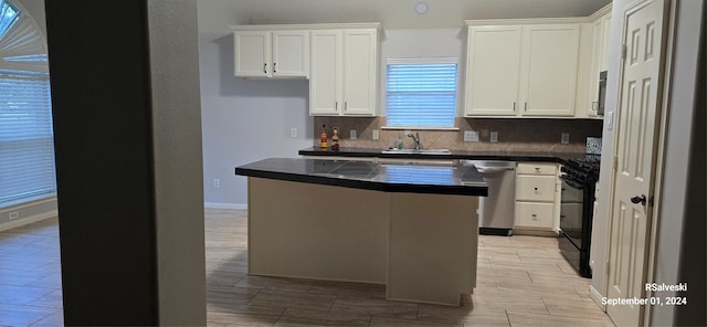 kitchen with dishwasher, black stove, white cabinetry, and sink