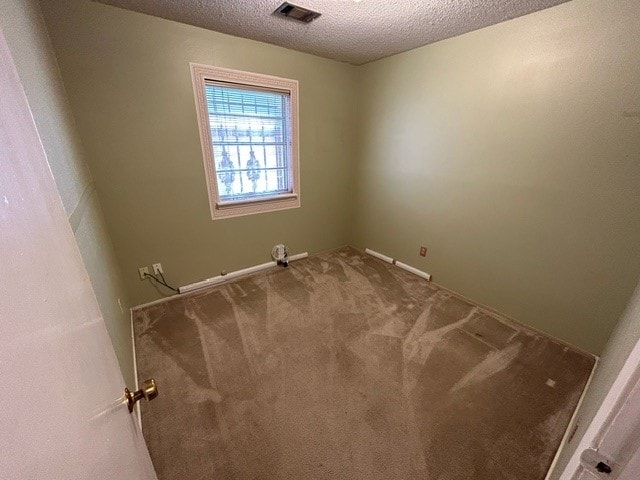 carpeted empty room with a textured ceiling