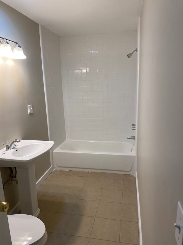 bathroom featuring tiled shower / bath combo, toilet, and tile patterned flooring