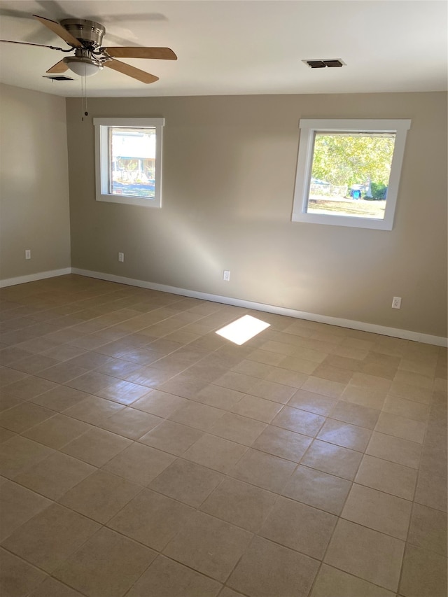 tiled empty room with plenty of natural light and ceiling fan