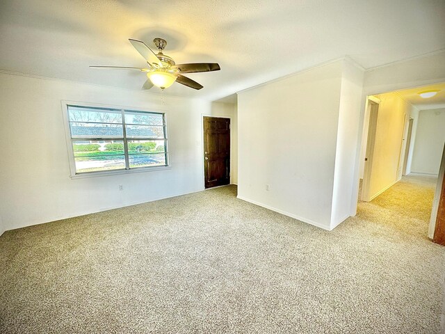 unfurnished room with ceiling fan, crown molding, and light carpet