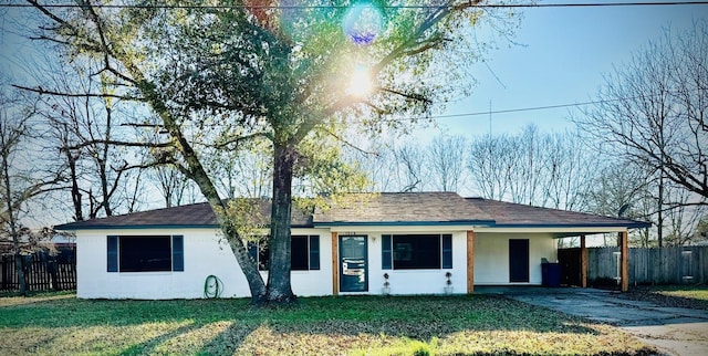 single story home featuring concrete driveway, fence, a front lawn, a carport, and stucco siding