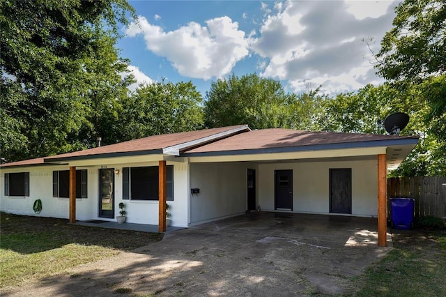 ranch-style house with a carport, concrete driveway, fence, and a front lawn