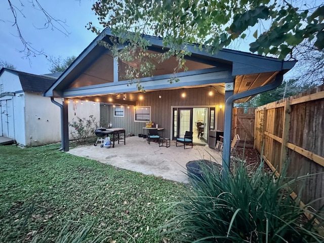 rear view of property featuring a yard, a storage unit, and a patio area