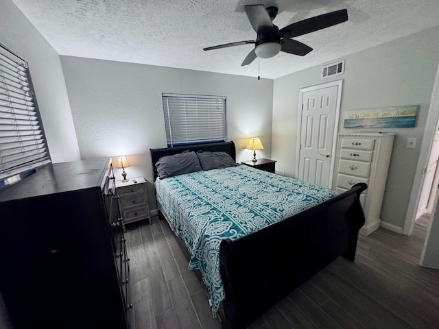 bedroom with ceiling fan, dark wood-type flooring, and a textured ceiling