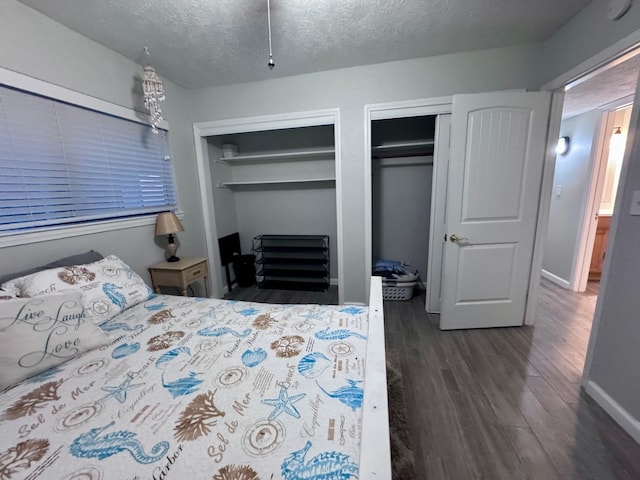 bedroom featuring dark hardwood / wood-style flooring, a textured ceiling, and multiple closets