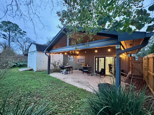 rear view of property featuring a yard, a patio, and a storage unit