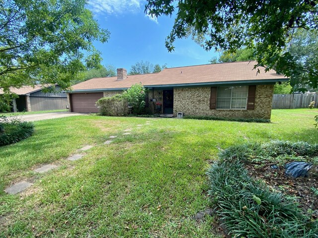 ranch-style home with a garage and a front lawn