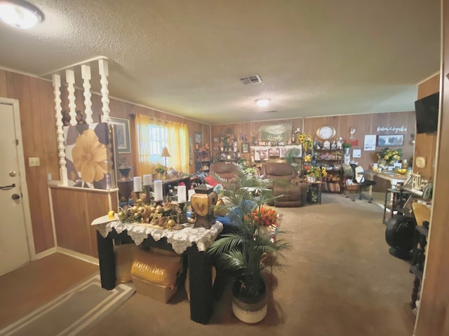 misc room with a textured ceiling, wood walls, and carpet flooring