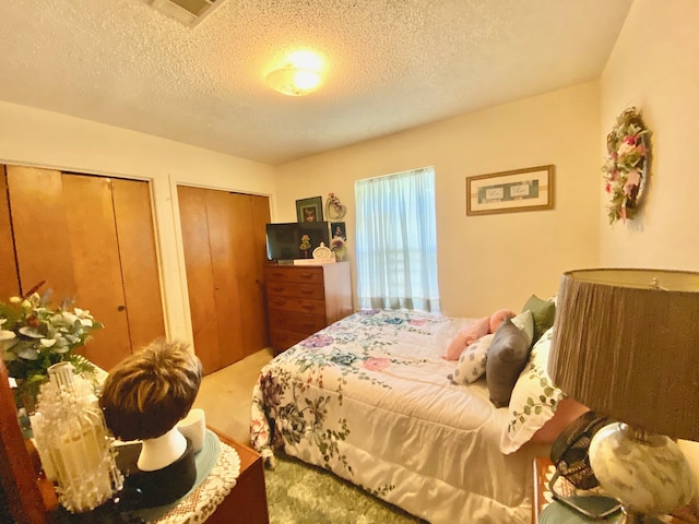 bedroom featuring two closets, carpet floors, and a textured ceiling