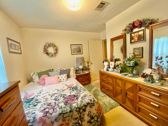 bedroom featuring light colored carpet and a textured ceiling