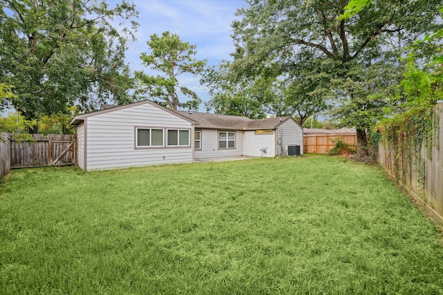 rear view of house with cooling unit and a lawn