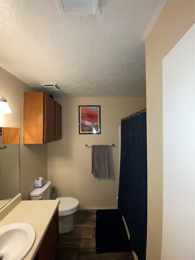 bathroom with vanity, toilet, hardwood / wood-style flooring, and a textured ceiling