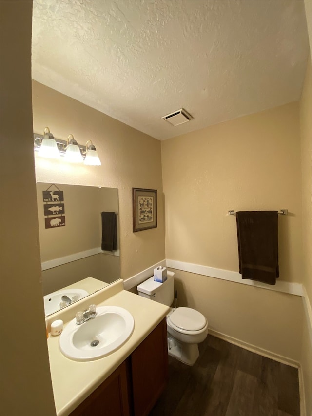 bathroom featuring hardwood / wood-style floors, toilet, a textured ceiling, and vanity