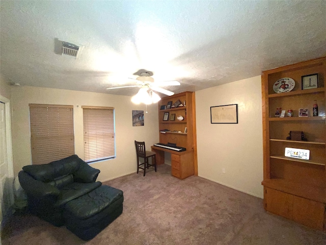 sitting room with a textured ceiling, carpet, and ceiling fan