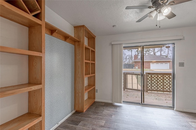 interior space featuring ceiling fan, a textured ceiling, baseboards, and wood finished floors