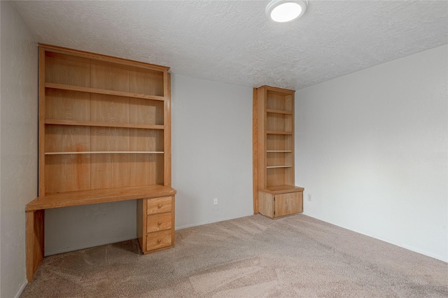 unfurnished office featuring light carpet and a textured ceiling