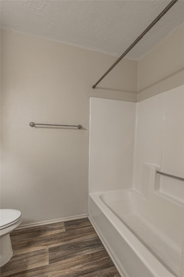 full bathroom with a textured ceiling, wood finished floors, toilet, and baseboards