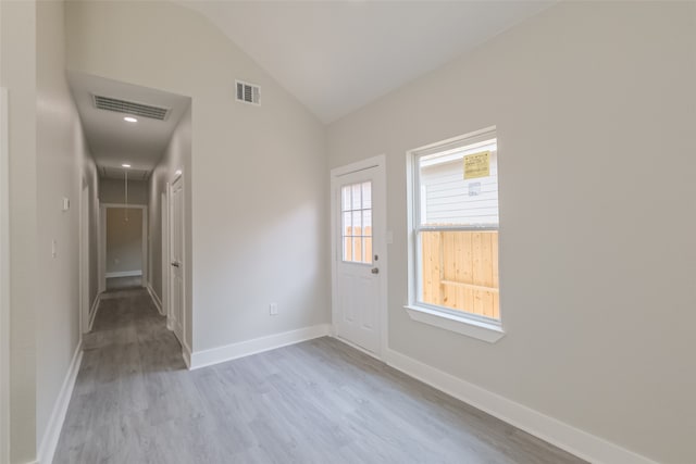 spare room with vaulted ceiling and light wood-type flooring