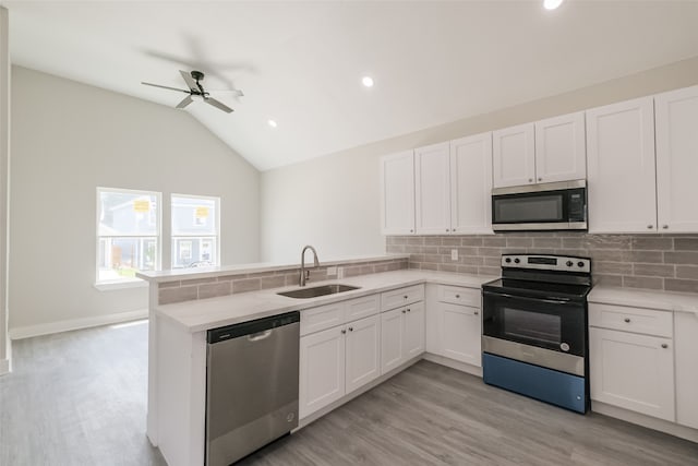 kitchen with kitchen peninsula, sink, ceiling fan, appliances with stainless steel finishes, and lofted ceiling