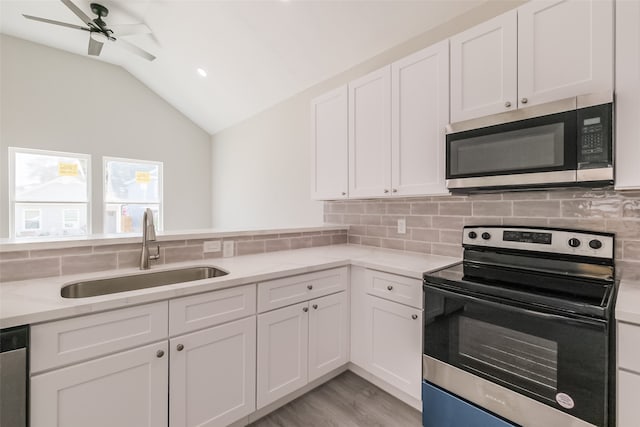 kitchen with white cabinets, stainless steel appliances, sink, lofted ceiling, and ceiling fan