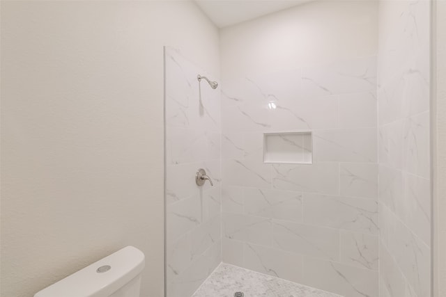 bathroom with toilet and a tile shower