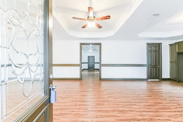 interior space with ornamental molding, a raised ceiling, hardwood / wood-style flooring, and ceiling fan