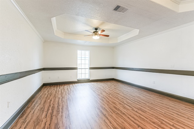 spare room featuring a tray ceiling, crown molding, hardwood / wood-style flooring, and ceiling fan