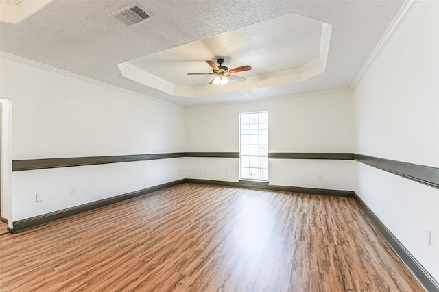 spare room with a tray ceiling, ceiling fan, hardwood / wood-style floors, and a textured ceiling