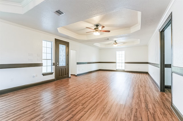 unfurnished room featuring crown molding, a textured ceiling, ceiling fan, a tray ceiling, and hardwood / wood-style flooring