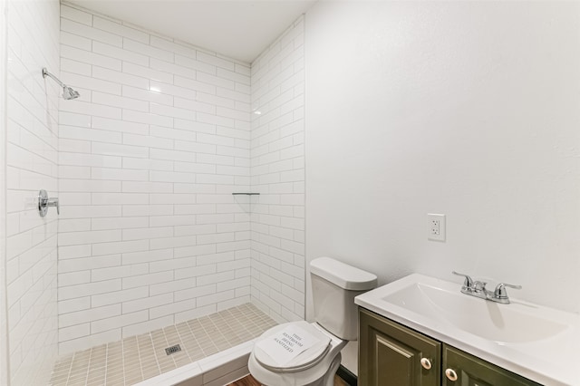 bathroom with tiled shower, toilet, and vanity