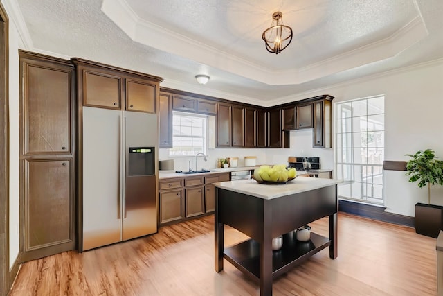 kitchen featuring crown molding, appliances with stainless steel finishes, light hardwood / wood-style floors, a raised ceiling, and a textured ceiling