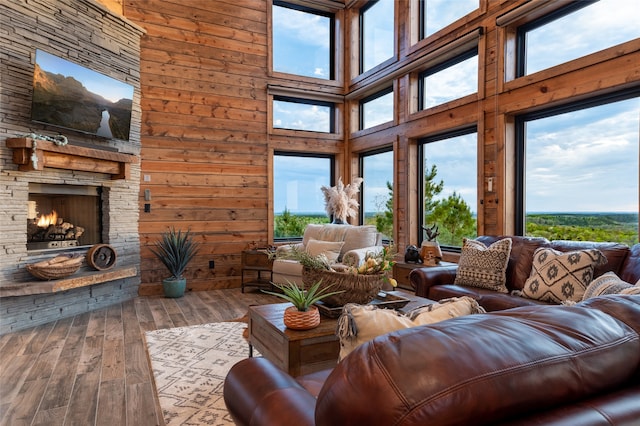 living room featuring a towering ceiling, a healthy amount of sunlight, and wood-type flooring