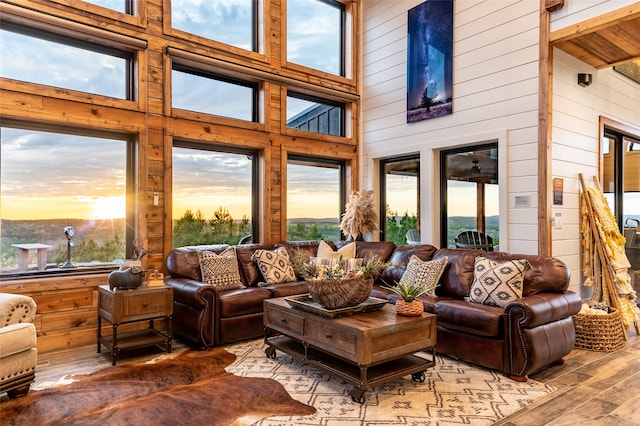 living room featuring plenty of natural light, hardwood / wood-style floors, high vaulted ceiling, and wooden walls