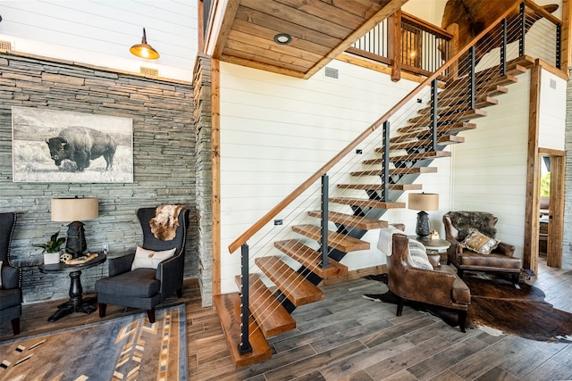 stairs featuring wood ceiling, a towering ceiling, wooden walls, and hardwood / wood-style flooring