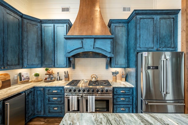 kitchen with custom range hood, backsplash, wood-type flooring, light stone counters, and premium appliances