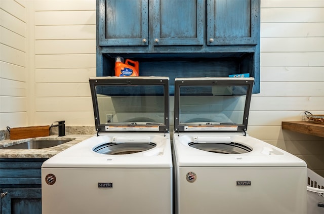 interior space featuring wooden walls, sink, cabinets, and separate washer and dryer