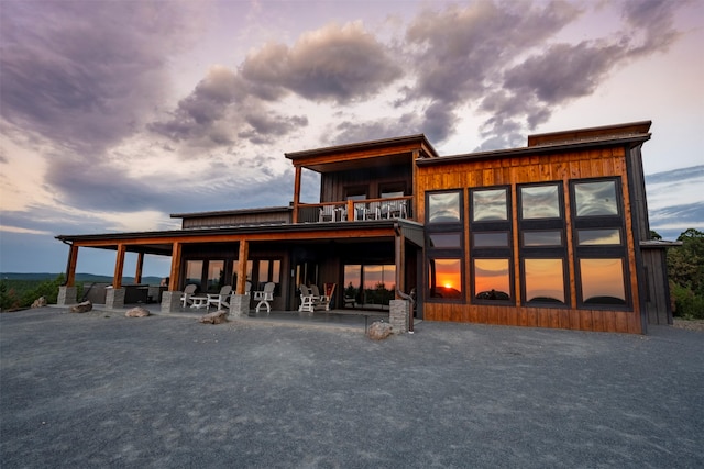 back house at dusk featuring a balcony